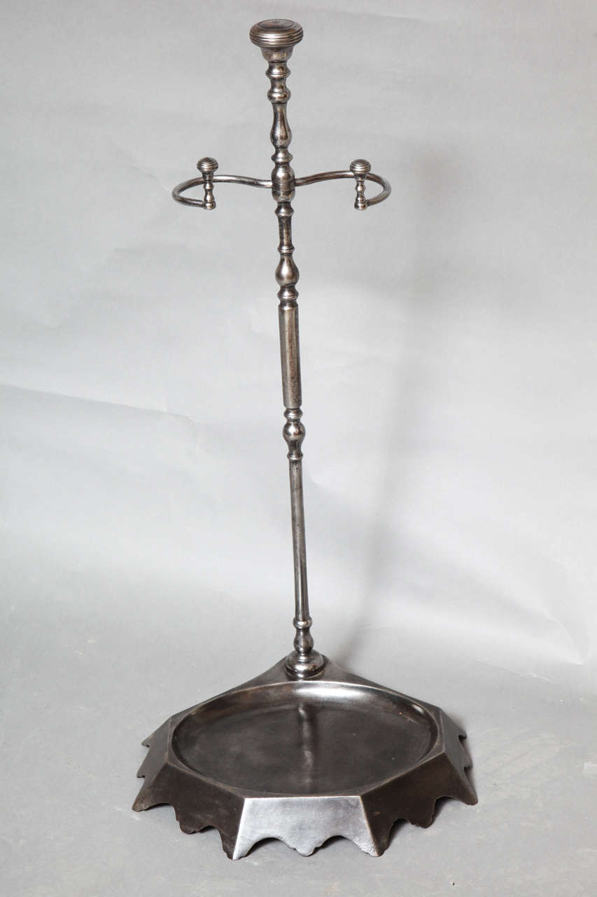 A 19th century English stand in gunmetal steel having turned shaft with knob finials to shaft and hook supports and shaped base with scalloped feet.