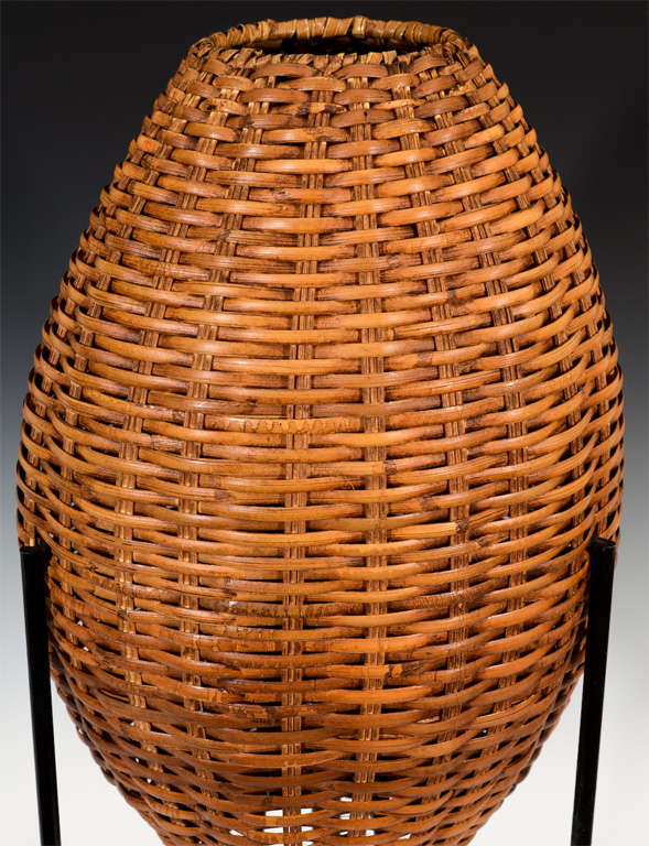 A pair of modern table lamps with tubular black metal tripod bases and woven egg shaped rattan wicker shades