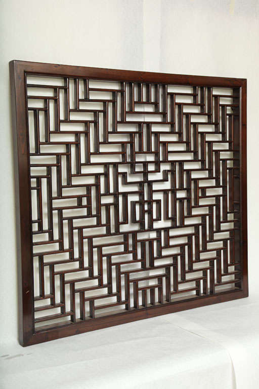 A Chinese lattice screen with a traditional wood pattern.  A wall hanging.  Mirrored backing available for additional price.