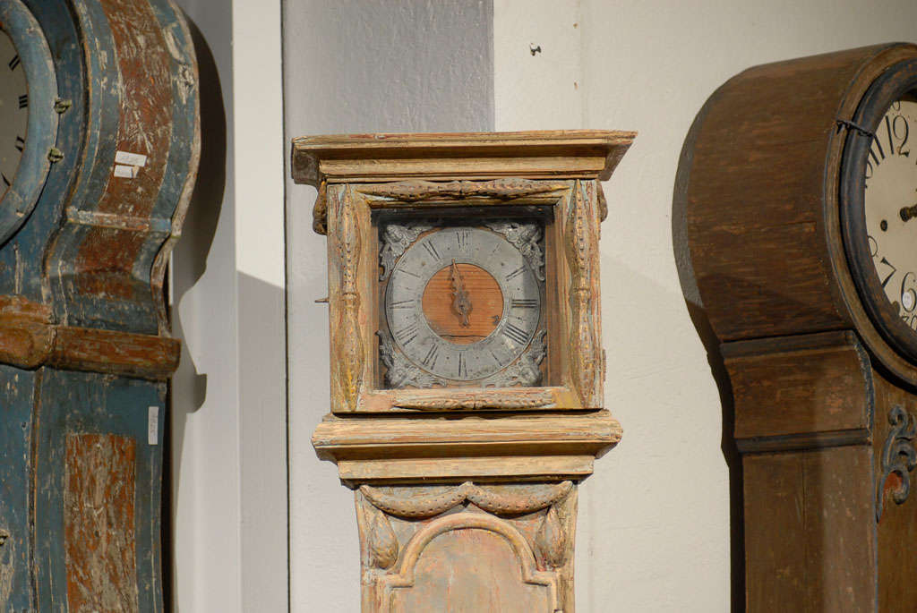 Cette horloge suédoise du XVIIIe siècle, parfois appelée horloge Mora, est quelque peu inhabituelle avec sa tête carrée et sa seule aiguille en bois d'origine, typique des premières horloges, alors que de nombreuses horloges suédoises ont plutôt une