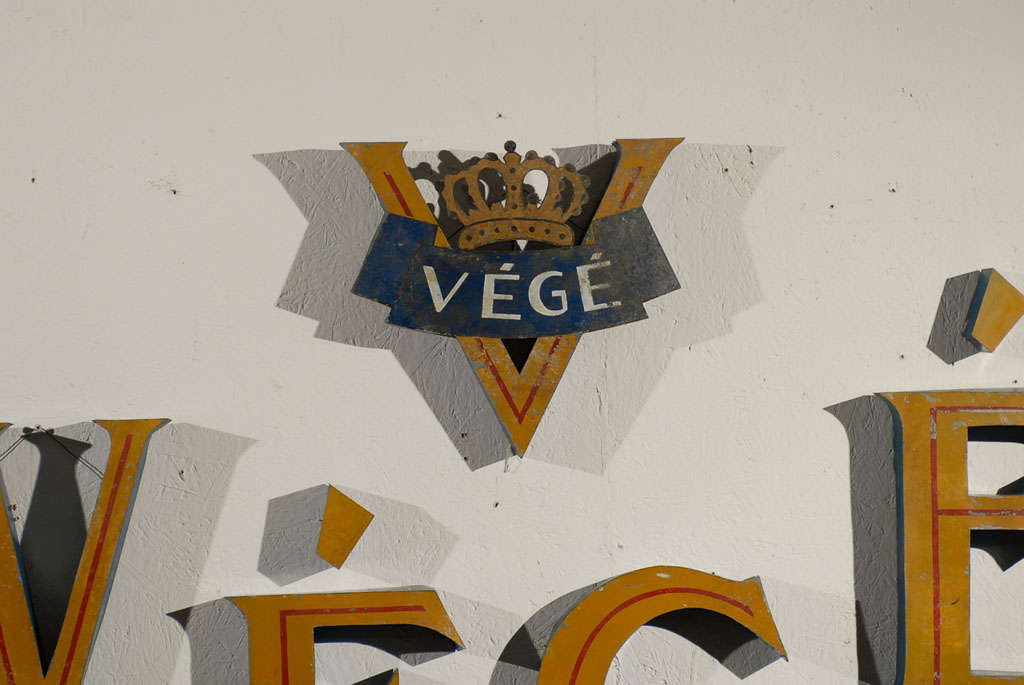 Ein belgisches, frei an der Wand montiertes Vintage-Ladenschild. Dieses Végé-Metall-Ladenschild kann je nach Geschmack individuell montiert werden. Es besteht aus den vier Buchstaben Végé und enthält das Logo, das von einer geschnitzten Krone
