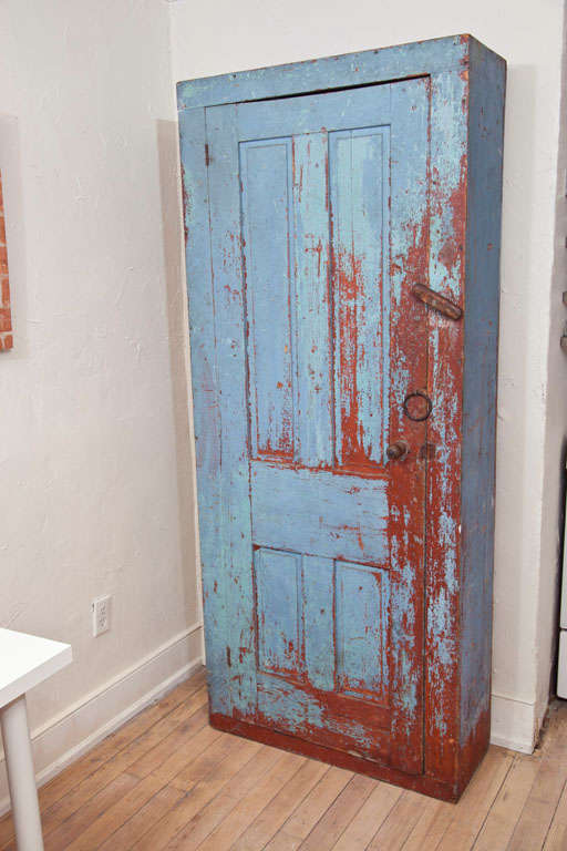 A Very Fine 18th Century New England Chimney Cupboard retaining a blue painted surface and raised panel door. Showing a paint history of blue over an earlier redwashed surface, with mortise and peg, and square head nail construction throughout.