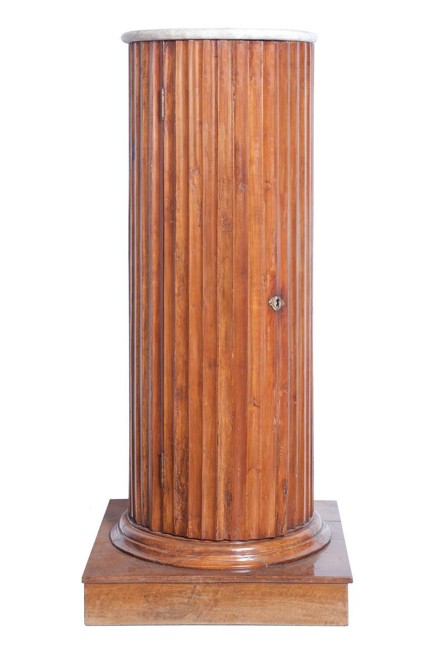 19th century cherrywood Empire column.

The column has a window on the front and a circular marble shelf on top.