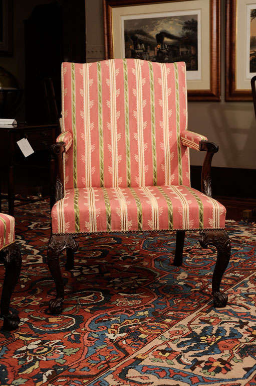 Each padded serpentine backrest above an overupholstered seat flanked by padded armrests with acanthus- and scroll-carved handholds on acanthus-carved voluted supports, raised on cabochon-C-scroll-and foliate-carved cabriole legs headed by