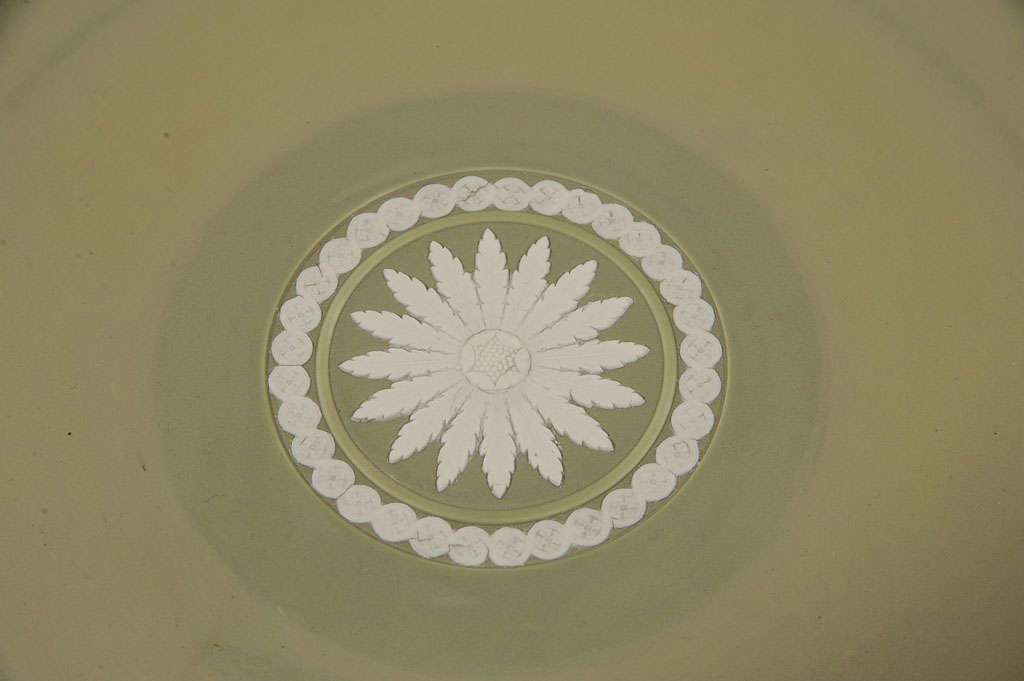 This 19th century, Wedgwood Jasperware platter has a neoclassical design sprigged in white showing mythological figures in applied bas-relief on an olive-green dipped ground. At its center is a white medallion consisting of a small star with 16