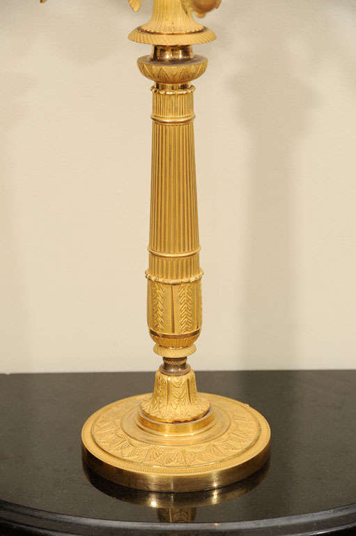 The reeded, round and tapered column mounted with one light and issuing five flying ho-ho birds with scrolling fish tails, each supporting drip pans decorated with palm leaves.