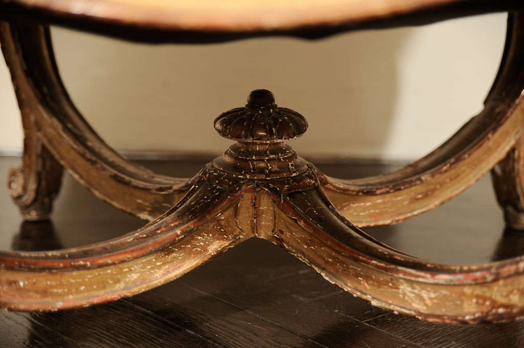 This French Napoleon III period giltwood stool has cabriole legs joined by stretchers joined by a central finial, all supporting a tufted upholstered seat.<br />
Provenance: Cynthia Phipps, Old Westbury, Lond Island, New York