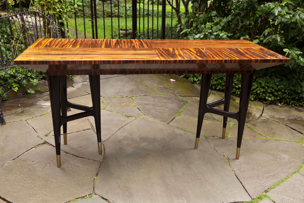 Panels of Macassar ebony cover the desk top which sits on tapering tripod blackwood legs. The face of the desk conceals three drawers, the center drawer containing compartments.