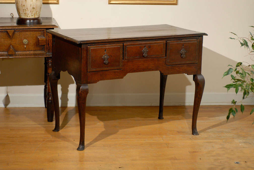 This is a very handsome English low boy also known as a side table.  The table is unusual with the cab legs and pad feet.  There are three drawers.  The pulls are not original piece.  Lowboys were very popular in the 18th Century.  They were often