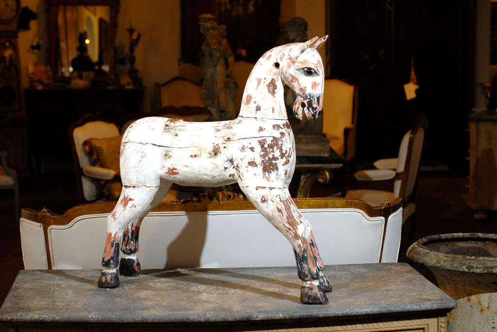 An English painted wooden horse sculpture from the 19th century with nicely weathered patina. This English wooden horse features a lovely weathered finish, whose rustic appearance compliments the archaic treatment of the surface beautifully. The