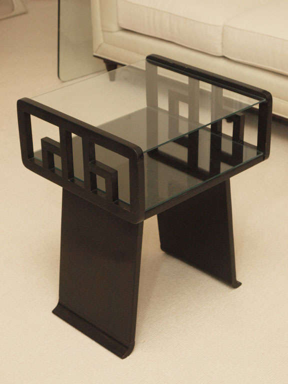 Two-tier ebonized end tables in the style of James Mont; out-flaring supports with fretwork at either side; glass plateaux; photographed with removeable glass lower shelf liner