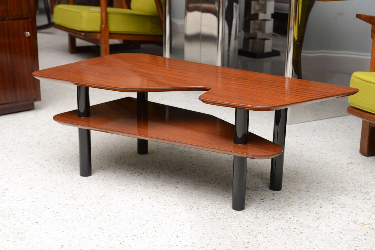 The free-form top with canted under edge above a second tier of geometrically shaped wood all joined by round ebonized legs.