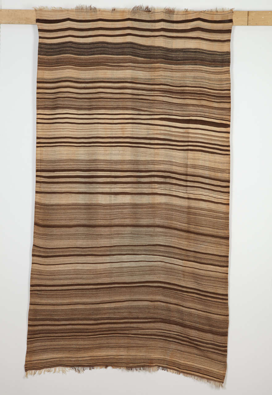 A rare and unique Berber flat-weave originating from the Anti Atlas region woven in alternating shades of brown and neutral. It is distinguished by a very fine, almost blanket-like handle. The asymmetrical, almost random character of the pattern is