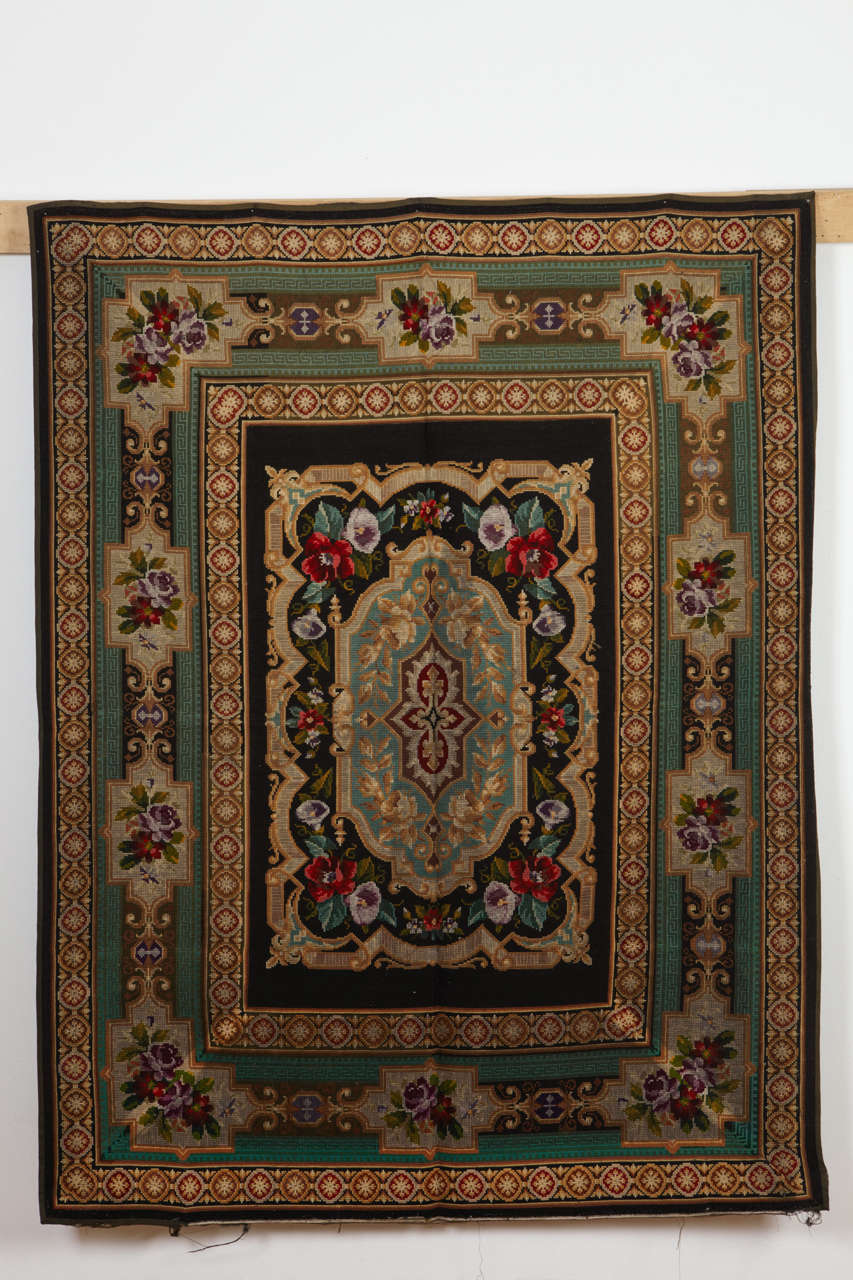 A very fine Victorian needlework rug woven on a black background with a beautifully articulated cartouche border. In original, intact condition.
