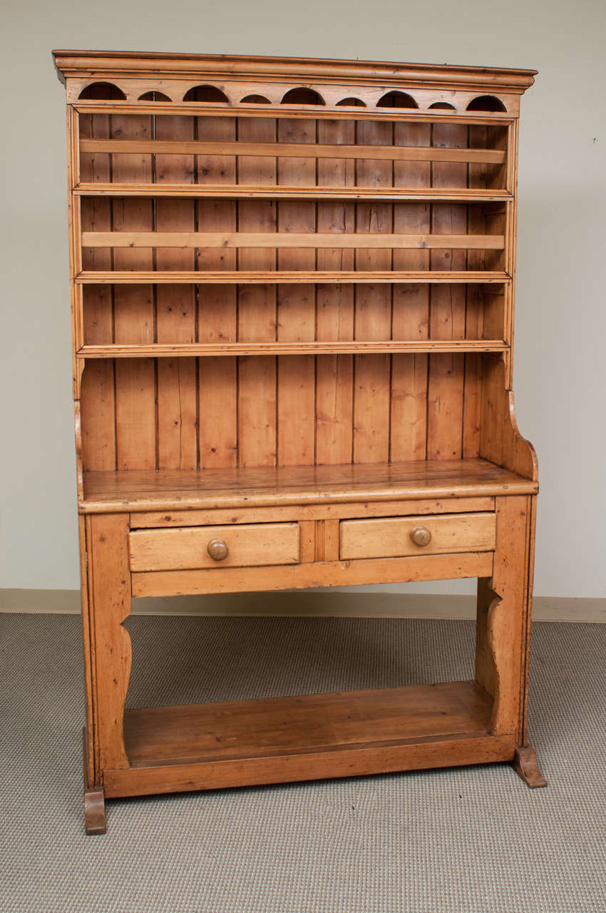 Even without a central splat to the base this is still known as a fiddle-front dresser.  This superb example of a one piece open rack dresser from Co. Mayo features a fretwork frieze above three plate shelves with tongue and groove backboards.  Two