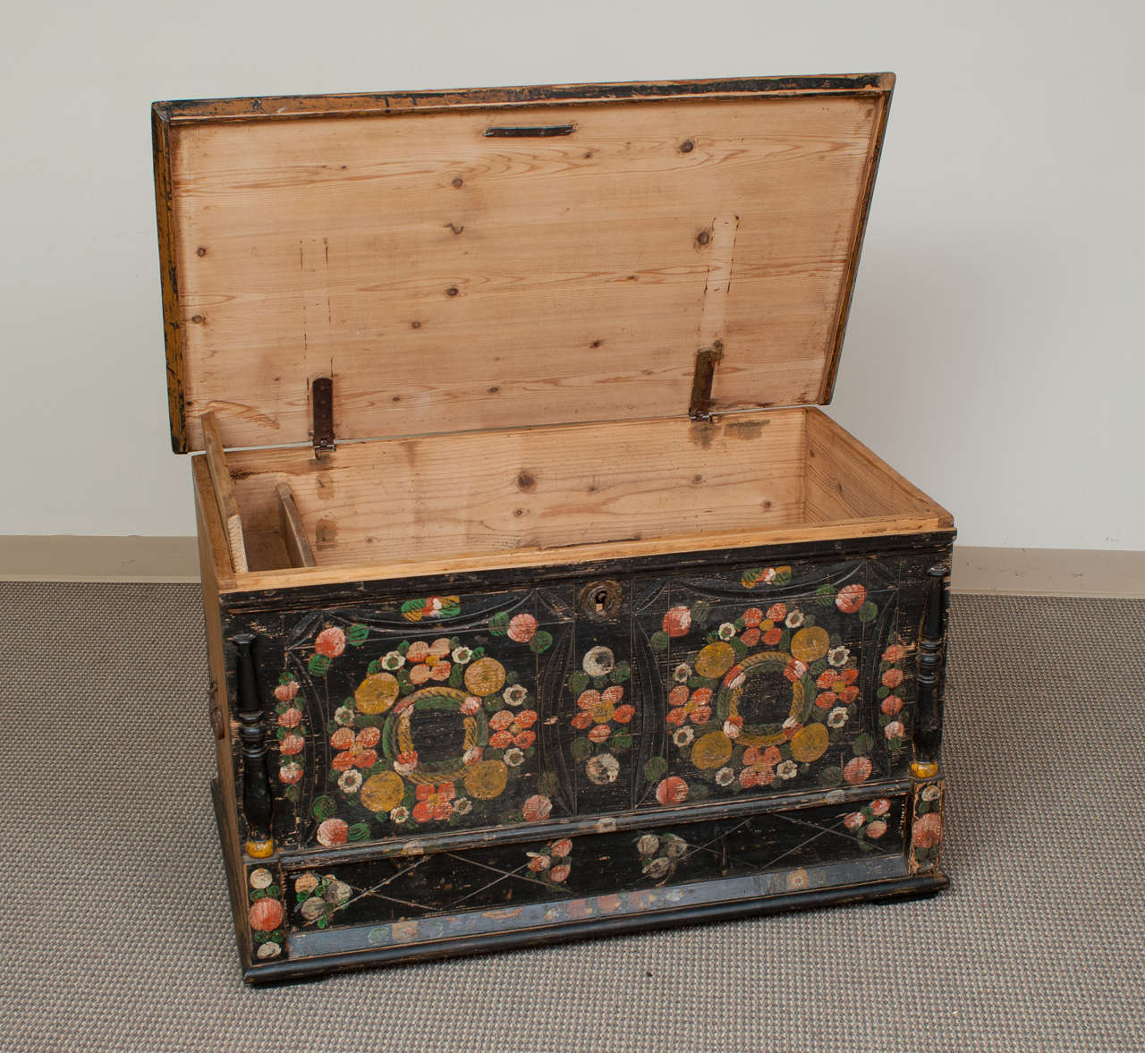 An outstanding faux mule chest featuring a black ground with hand-carved pattern and original stylised polychrome floral decoration to the front flanked by split balusters.  Well-worn mustard paint to the top and sides.  The interior has a full