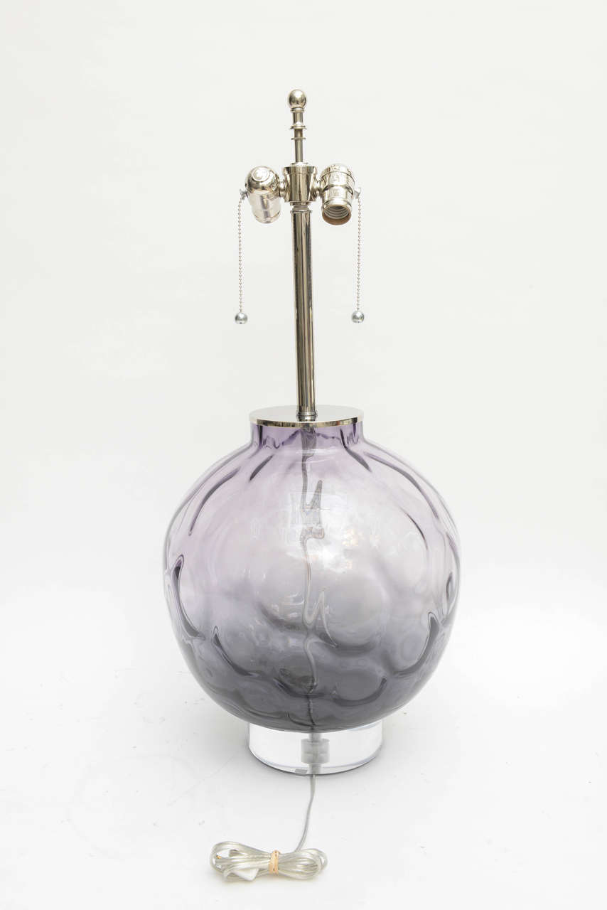 This beautiful pair of Murano glass lamps are in a clear-purple-violet coloration with nickel-plated trim and a Lucite base.

The round form is in a mottled-dimple pattern.

Note: Measures 28