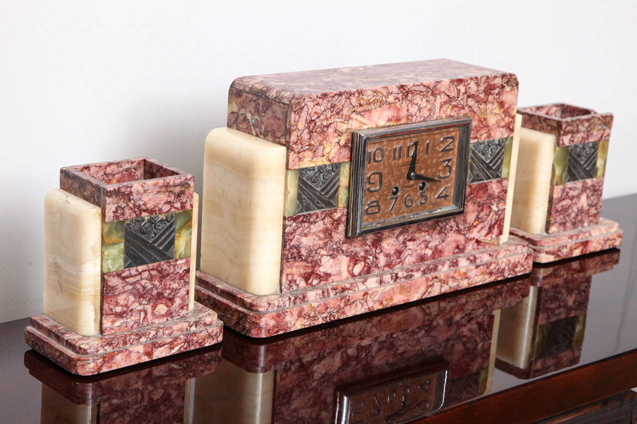 A rose siena marble and onyx Art Deco mantel clock set of three with two matching garnitures. The clock measures: 15.5