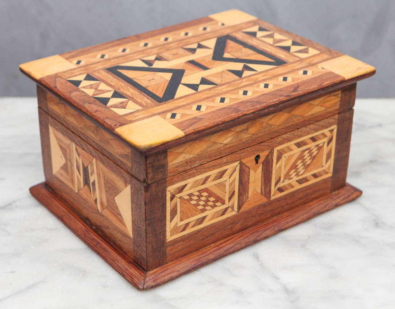 This is a great folk art box with light and dark woods in geometric patterns throughout. The interior has been recently restored with Japanese Rice Paper and retains the original blue velvet lining in the tray.