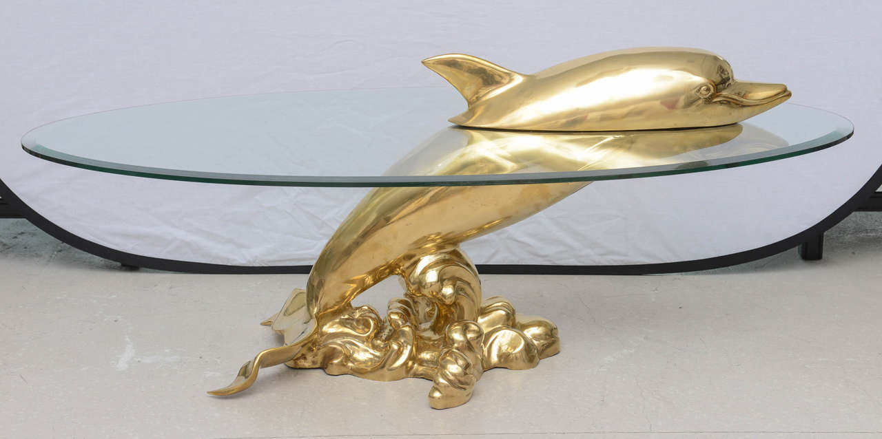 Vintage polished brass table in the form of a dolphin cresting above the water (glass top)