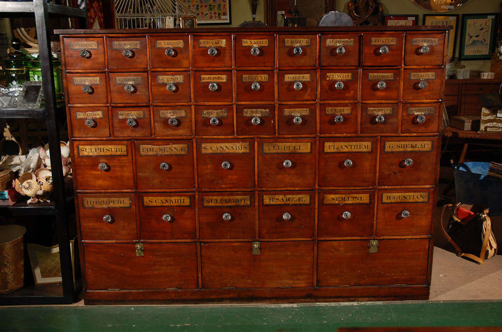 C. 1850 large English apothecary, general store, seed cabinet. This is a magnificent piece of history. This old walnut cabinet is a fine example of the workings of a general store of yesteryear. Judging from the old labels inside two of the drawers,