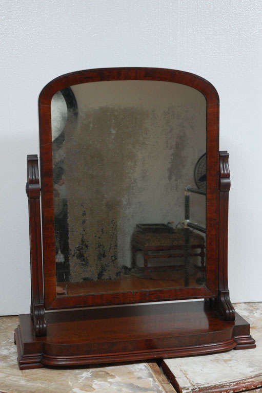19th Century mahogany veneer dresser mirror with fine patina. Mirror mounted on the arms of the mahogany base and has swivel mechanism. Lovely, deep patina to the mahogany veneer. Very good condition to all parts.  Mirror frame measures 26