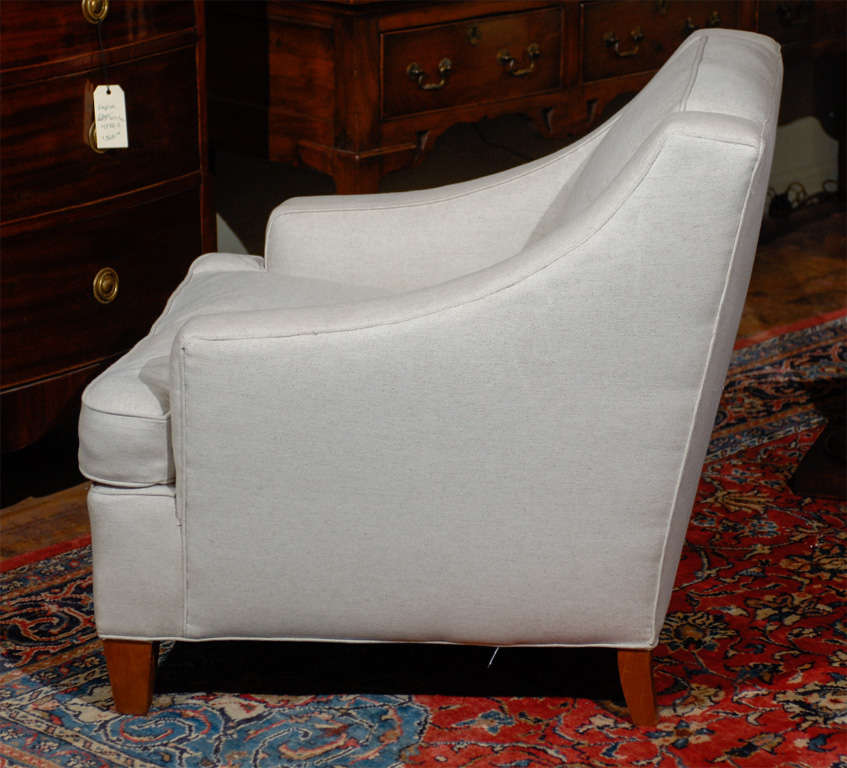 A pair of French linen upholstered club chairs from the 19th century. This pair of French 19th century club chairs features square backs with sloping arms over upholstered seats with loose cushions. The chairs are upholstered in a light colored