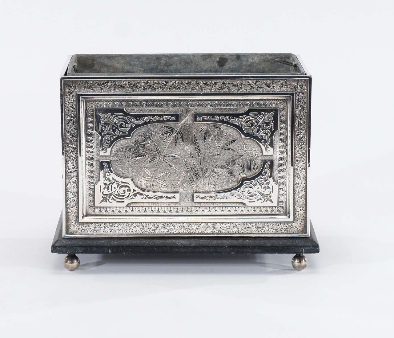 A rare and wonderful example of Aesthetic Movement decoration at it's finest. This silver plated planter sits on a stone or marble base, atop four round silver feet. It is decorated on all four sides with masterful engraving using all the motifs