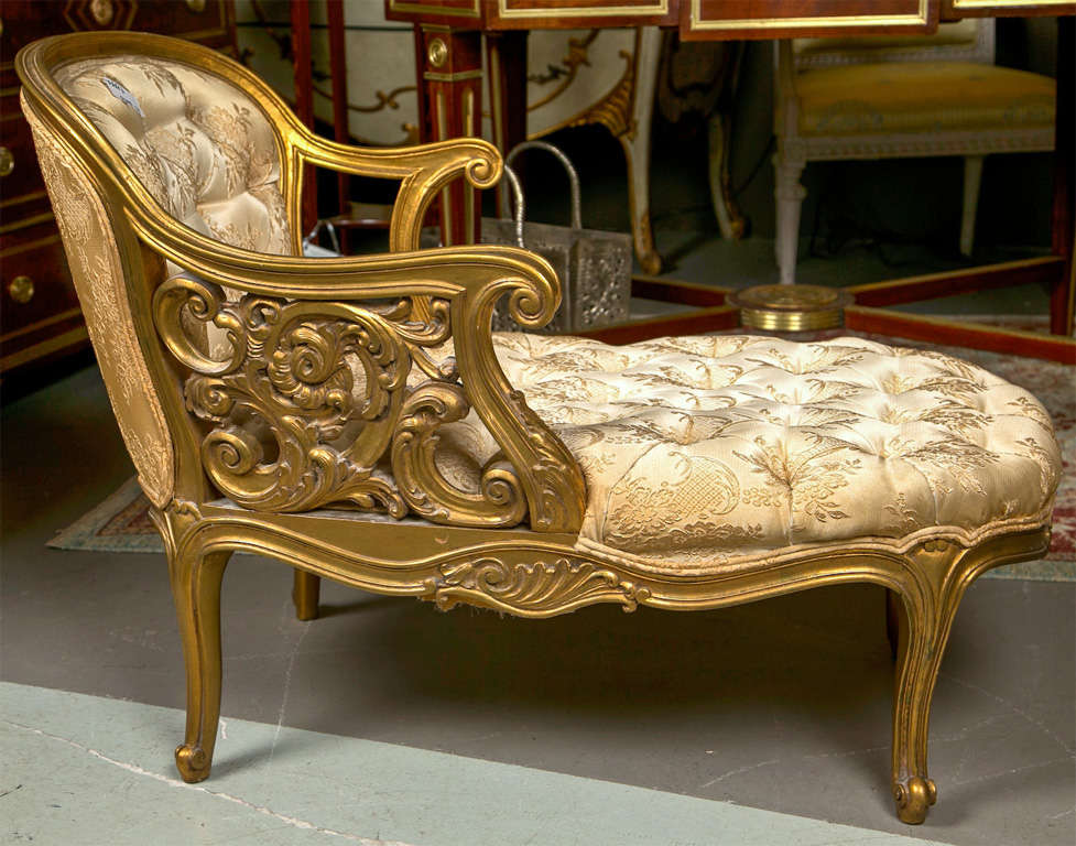 An attractive French Rococo style diminutive gilded recamier, circa 1930s, overall gilded, the tufted back with downswept scrolled arms, one with beautiful pierced carving of scroll-work, tufted seat, raised on cabriole legs.