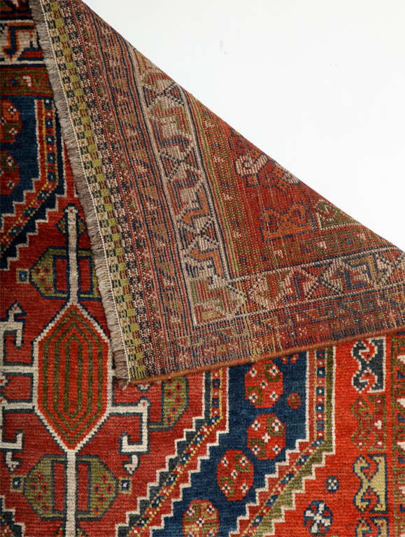 This Persian Qashqai carpet circa 1900 consists of pure handspun wool and organic vegetable dyes. Its pile is hand-knotted and it is in excellent antique condition with rich shades of red, blue, green and navy throughout its double medallion, field