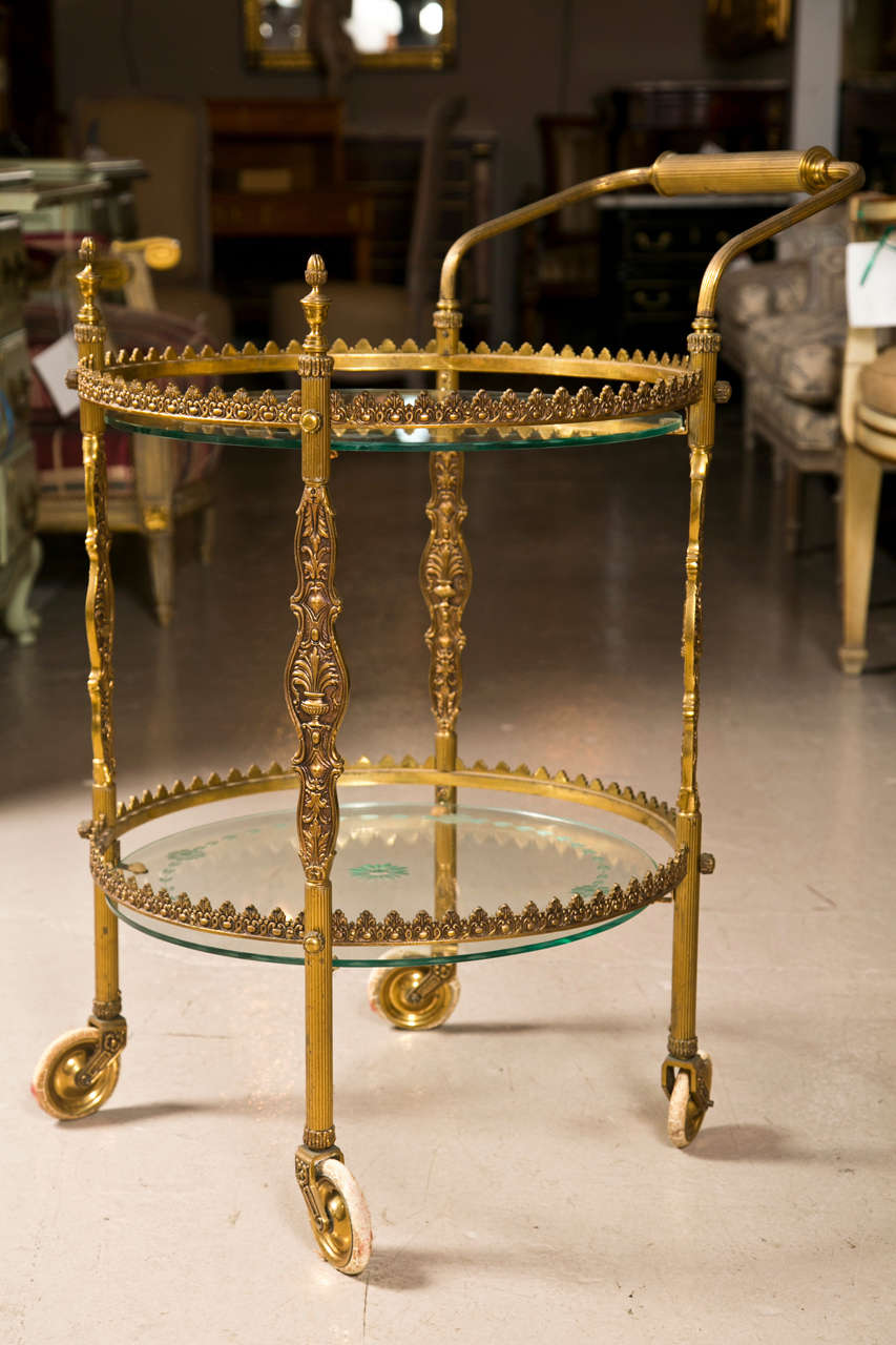 Spectacular French Art Deco style gilt bronze bar cart, circa 1940s, Fine two tier rolling bar cart. The lower and upper glass shelves having etched decorated borders. Finely chased bronze work.