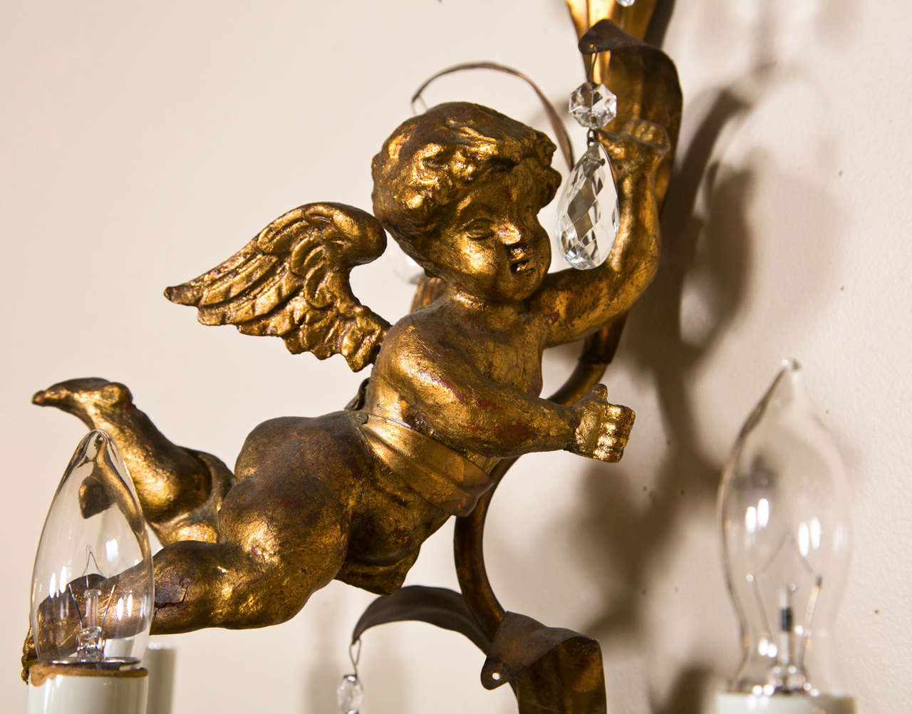 French Marie Therese style gilt-brass wall sconces, each decorated with foliate and an opposing cherub figure, each has three lights and decorated with crystals.