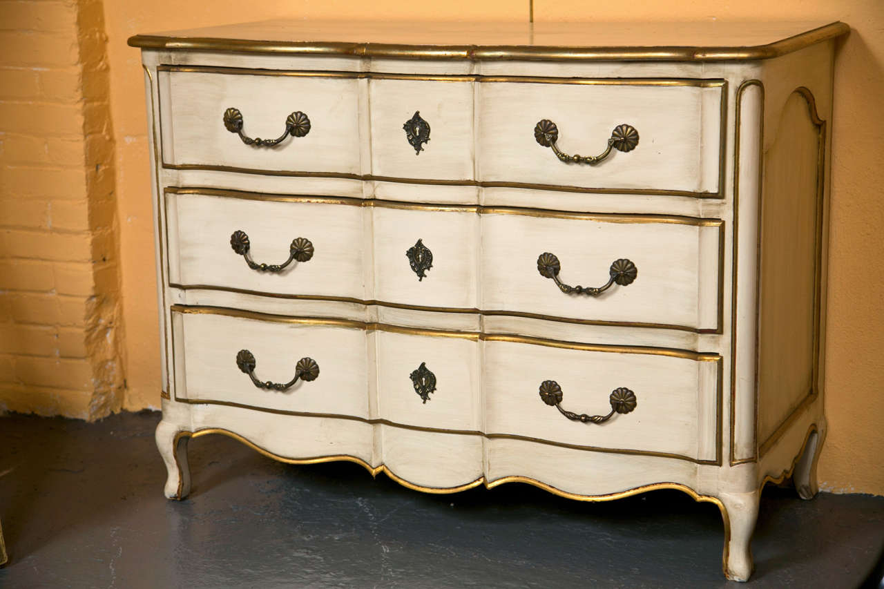 French Louis XV style distress painted and parcel-gilt commode, the shaped top over a conforming case fitted with three drawers of oak secondaries, raised on a scallop-form apron and short cabriole legs. Stamped Jansen.