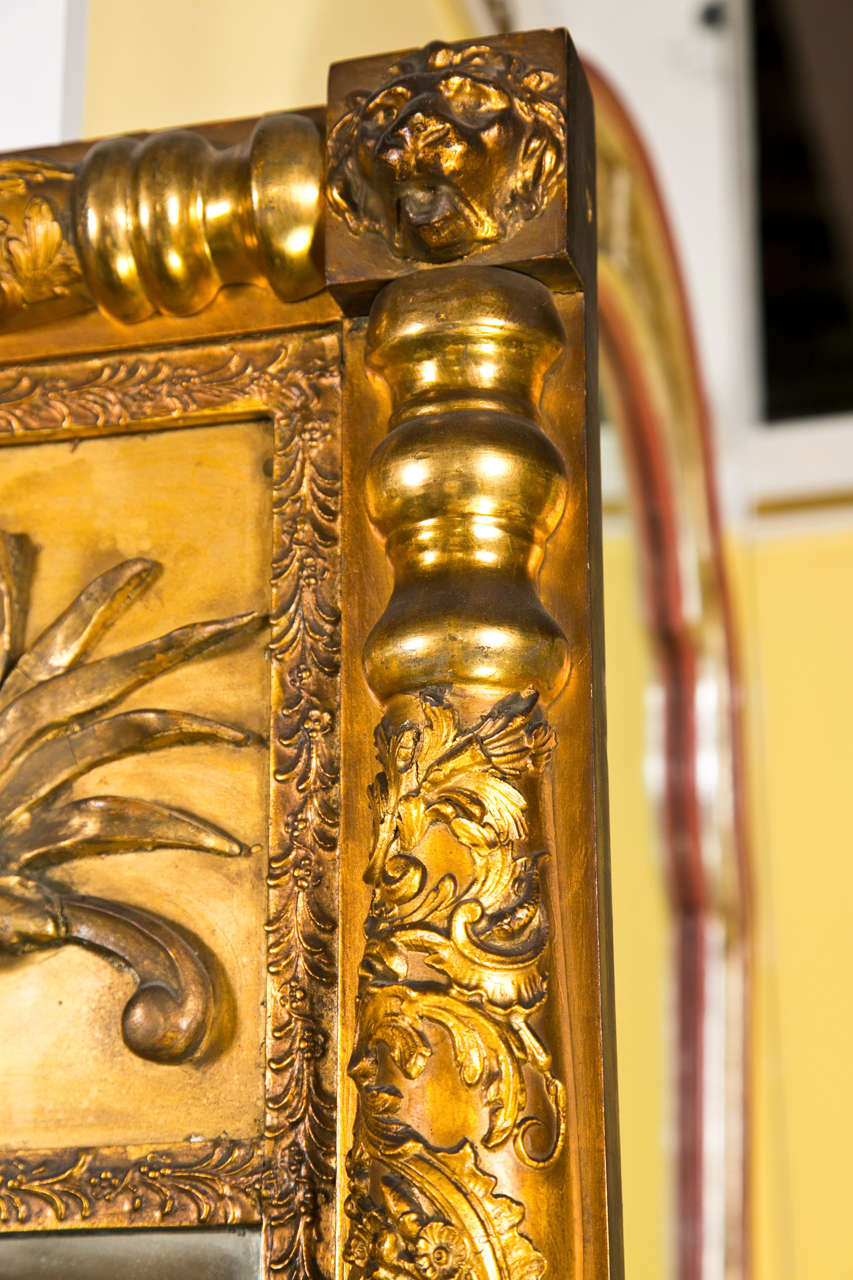 Miroir en bois doré de style Empire français, vers le 19e siècle, cadre finement sculpté, le miroir flanqué de montants à balustres cannelés, quatre coins décorés d'un motif de tête de lion.