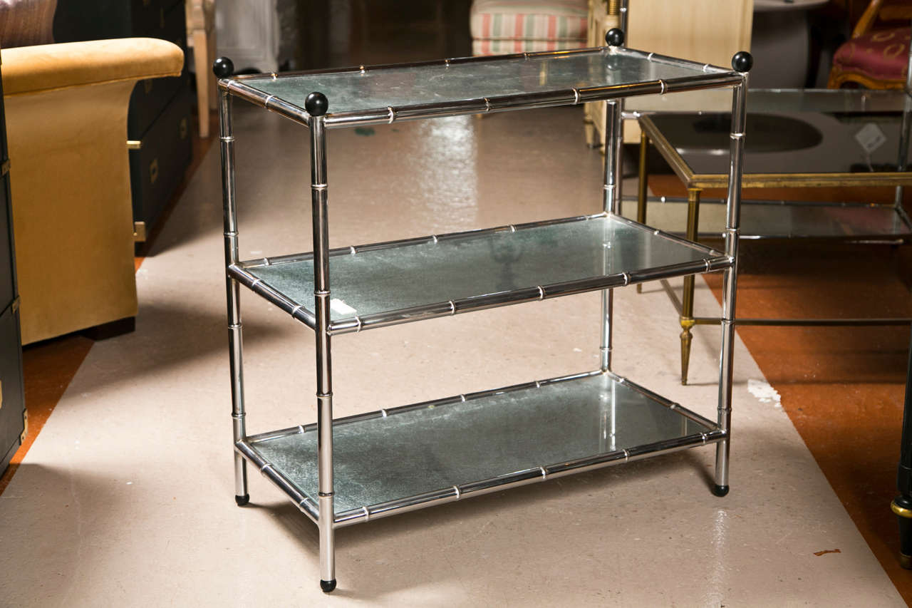 Pair of mid-century modern etageres, each has chrome faux-bamboo style frame, consists of three silver-leaf glass tiers, decorated with black sphere finials.