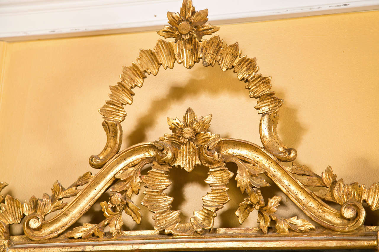 Decorative giltwood mirror, the rectangular frame surmounted by a mirror insert trim, the top and side decorated with foliage and scrolls.
