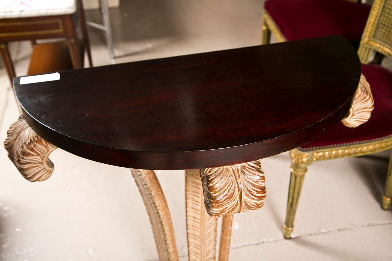 Mahogany demilune console table, circa 1960s, the half-moon shaped top supported by a distress painted plume shape pedestal, raised on a half-moon plinth.