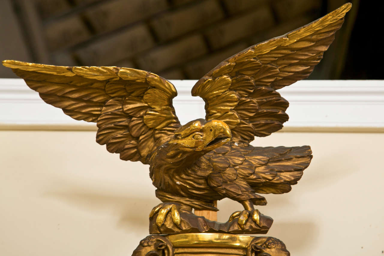 A charming giltwood convex mirror in the Federal style, circa 1920s, the convex glass surmounted in a circular annulated frame, the top decorated with an eagle crest flanked by foliate.