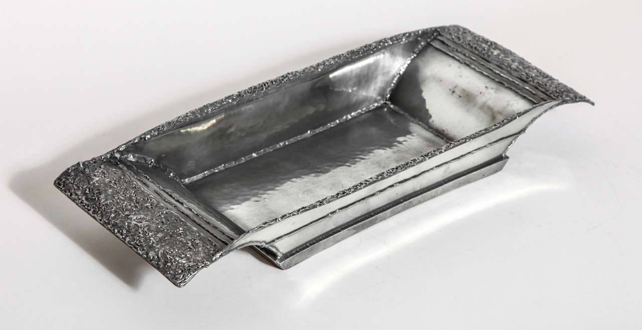 Large hand-wrought rectangular dinanderie martele pewter coupe with curved handles.
Signed: ''R. Delavan'' on body 
Stamped: ''DEPOSE/ R. DELAVAN/ DECORATEUR/ PARIS/ ETAIN D'ART/ TRAVAIL AU MARTEAU'' underside

*Variety of other Rene Delavan pieces