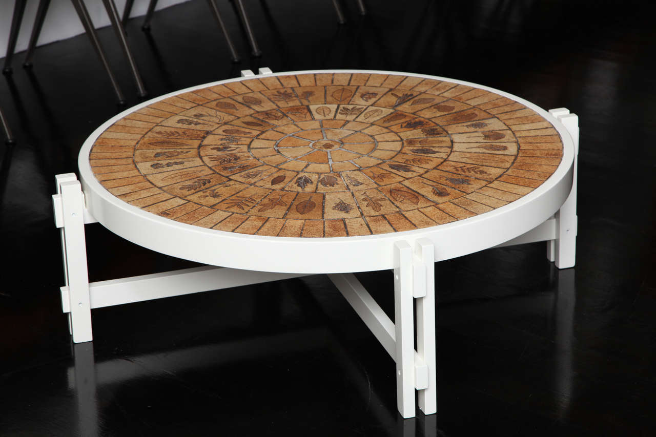 A fantastic- signed coffee table by Roger Capron with an organic pattern of leaf pressed tiles in tones of brown, tan and beige.
The base is white lacquered wood.