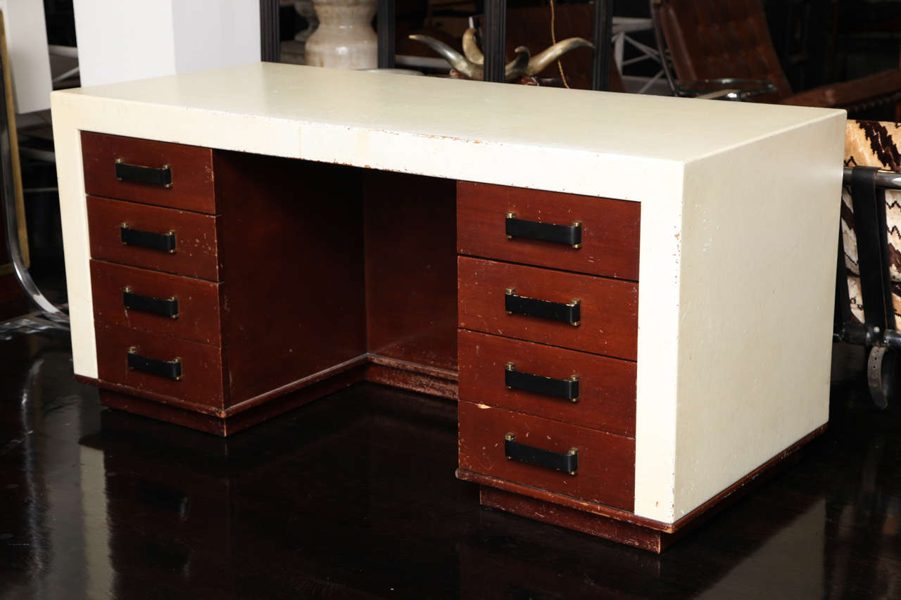 An early Paul Frankl desk with original cork top and sides, 
two bays of four drawers with original hardware. Wood is mahogany with a low lustre finish. The front of the desk has a book shelf as a decorative feature.
Leg opening 24