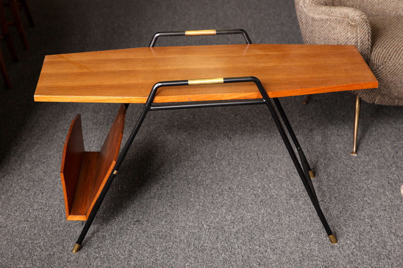 Wonderful cocktail table with magazine rack on side, made in 1955 in Italy. Very unusual form. Top and rack in walnut with legs in iron brass. Beautifully made.
 
