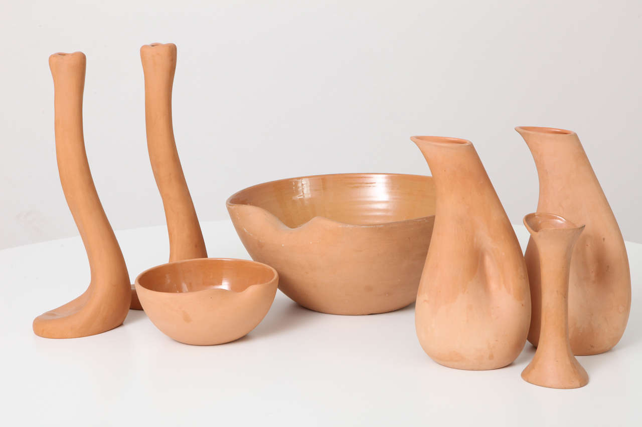 Beautiful collection of vintage terracotta pieces by Elsa Peretti for Tiffany. Seven-piece set includes a small and large thumbprint bowl, two candlesticks, two carafes, and a vase, all with glazed interior and matte exterior. Organic, fluid, and