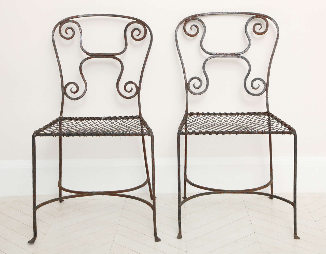 A pair of early 19th century French painted wrought-iron side chairs
with open back and lattice seat