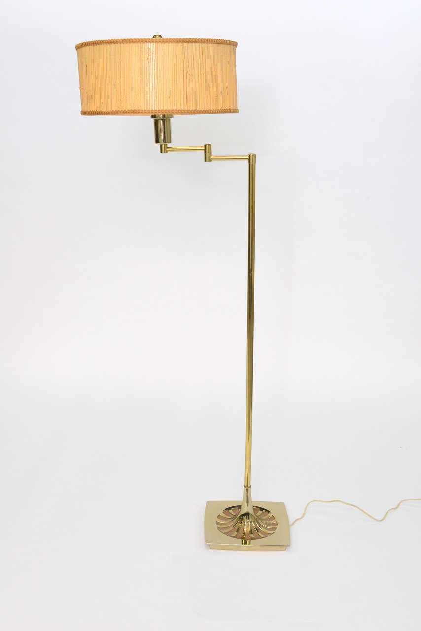 Wonderful brass floor Lamp by Laurel Lamp Co. with a soft edge square base featuring a stylized starburst design. Having a Nessen style articulating arm ending in a milk glass difusser and original grass-cloth barrel shade. Three level medium base