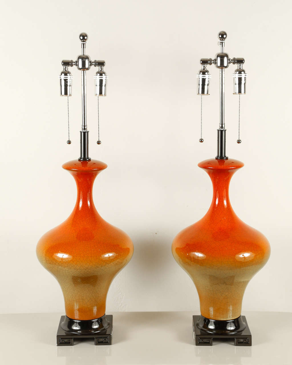 Beautiful pair of ceramic lamps with a yellow to orange ombré glaze.
The lamps are mounted on polished black nickel bases and they have been newly rewired with nickel double clusters that take standard light bulbs.
         