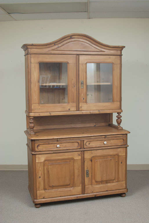 A very handsome Baroque-style glazed dresser featuring a bonnet-topped upper section with two glazed wide-swinging doors above a two door two drawer base with pull-out breadboard and original ceramic knobs.
