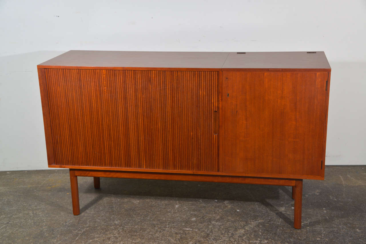This unique credenza offers a tambour door on one side and a door with lock other side. Part of the top lifts up and reveals a compartment for storage. This piece measure 61.5