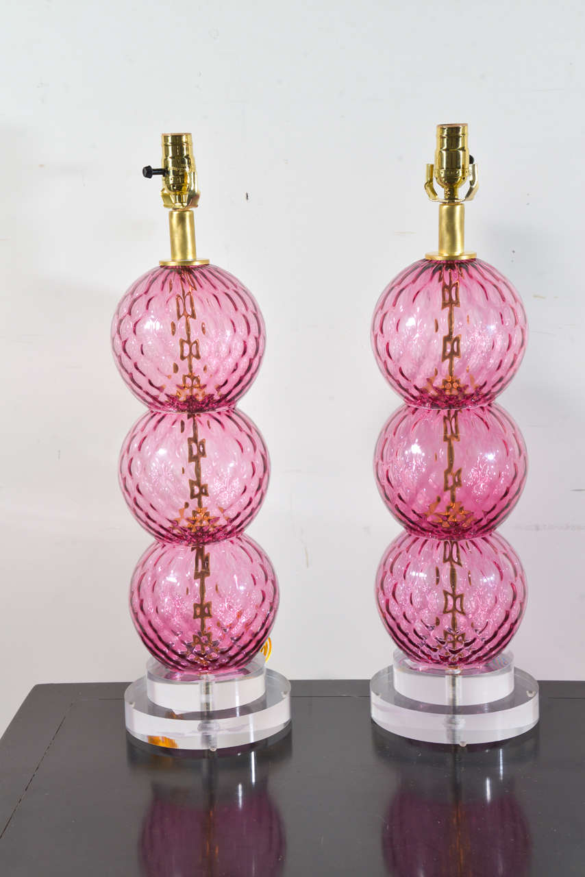 A pair of vintage table lamps, each with three pink Murano glass orbs stacked on each other. Each measure 24.5
