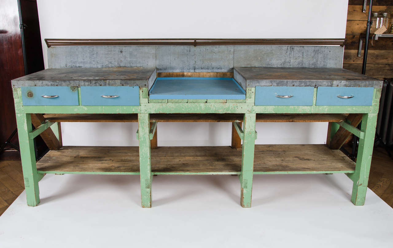 A reclaimed vintage counter made from pine, with a metal top work surface and powder blue drawers underneath. The central blue panel may be removed to reveal stripped pine boards, flanked by metal top and splash back, surmounted by a metal rail.